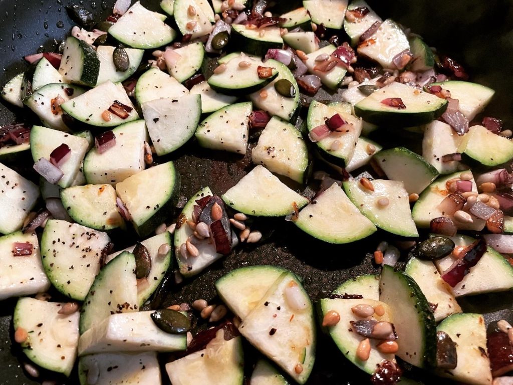 Zucchini mit Zwiebeln, Sonnenblumen- und Kürbiskernen vorher anbraten.